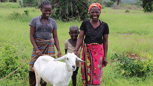 Ziegen gegen Armut Eine Familie steht mit ihrer Ziege auf einer Wiese.