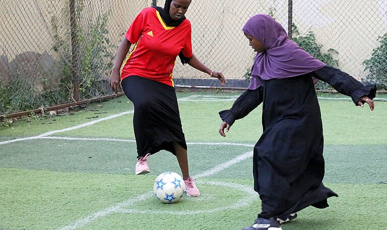 Zwei Mädchen spielen auf einem Fußballplatz