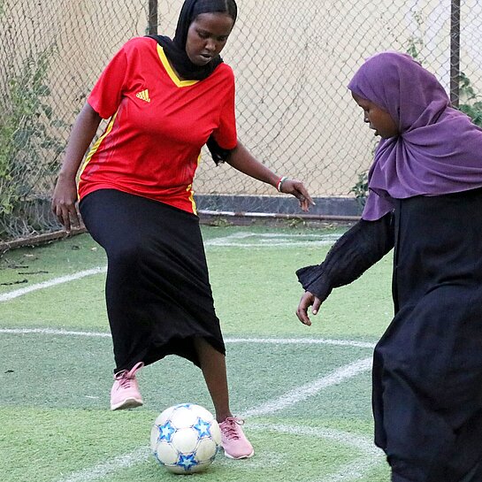 Zwei Mädchen spielen auf einem Fußballplatz