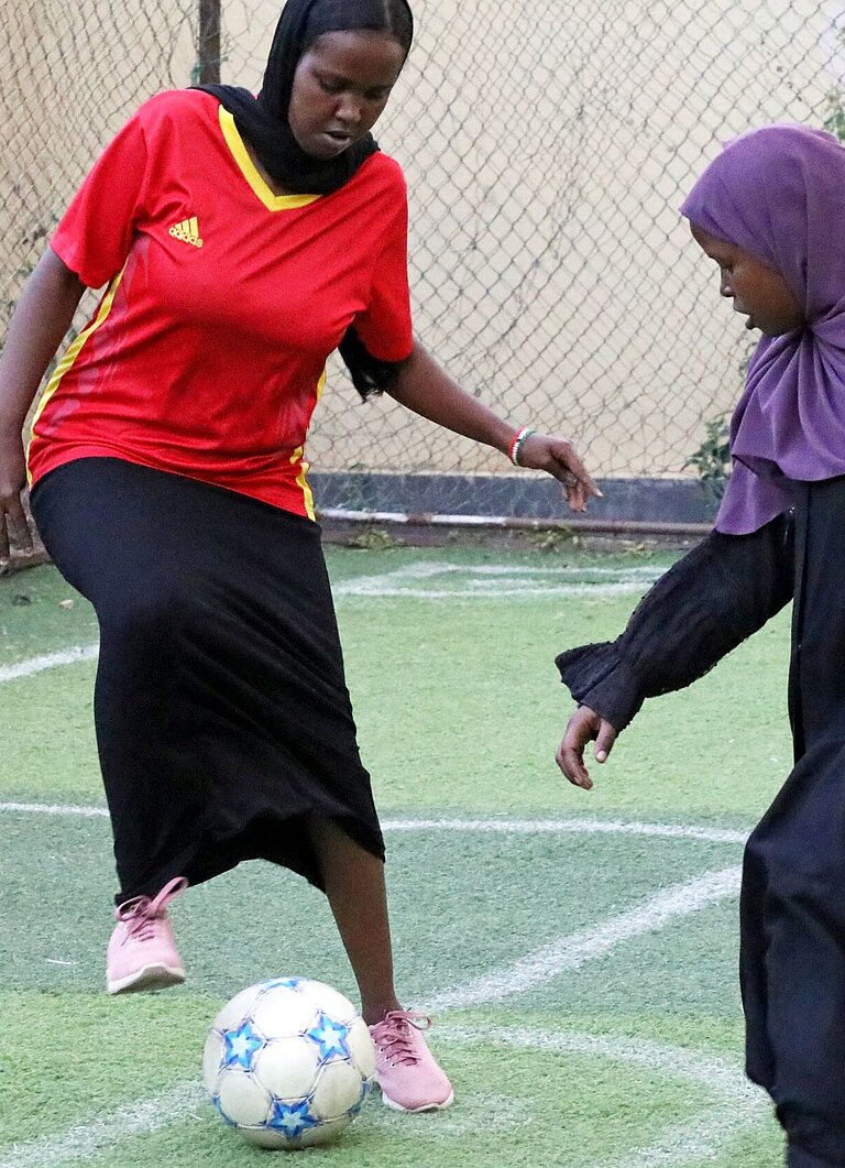 Zwei Mädchen spielen auf einem Fußballplatz