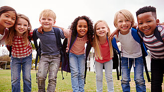 Kinder stehen gemeinsam Arm in Arm in einem Kreis