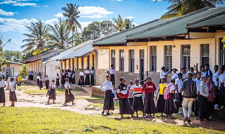 Mädchen und Jungen stehen vor einer Schule, die Plan International in Mosambik gebaut hat
