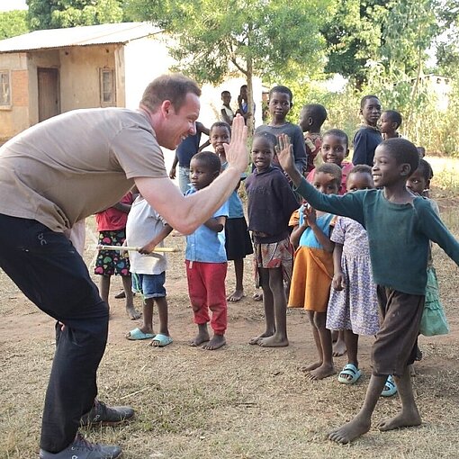 Felix Loch gibt einem malawischen Jungen ein High-Five