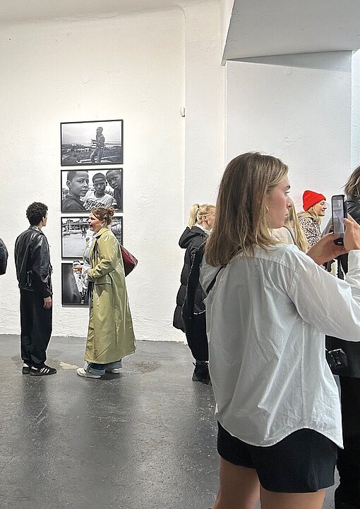 Menschen in hellem Ausstellungsraum mit schwarz-weißem Foto im Hintergrund