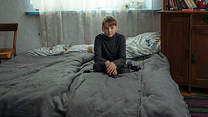 Ein Junge sitzt auf einem Bett mit warmen Decken