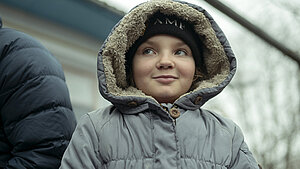 Junges Mädchen mit dicker Winterjacke und Kapuze auf dem Kopf