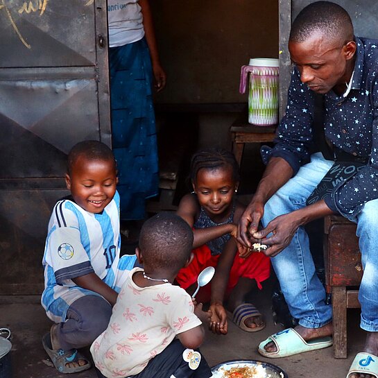 Ein Vater verteilt Essen an drei kleine Kinder