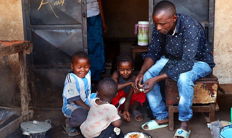 Ein Vater verteilt Essen an drei kleine Kinder