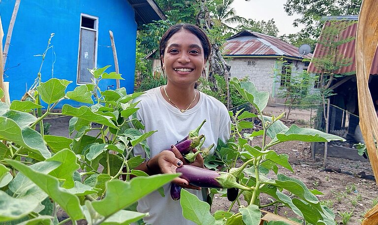 Anita erntet Auberginen in ihrem Gemüsegarten 