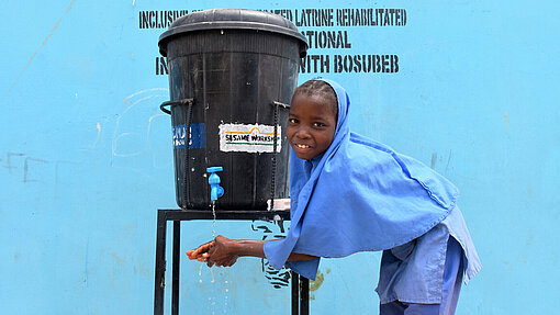 Handwaschanlage für Schulen Ein Mädchen nutzt eine neue Handwaschstation von Plan International.