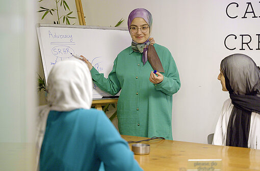 Drei junge Frauen mit Kopftuch in einem Konferenzraum